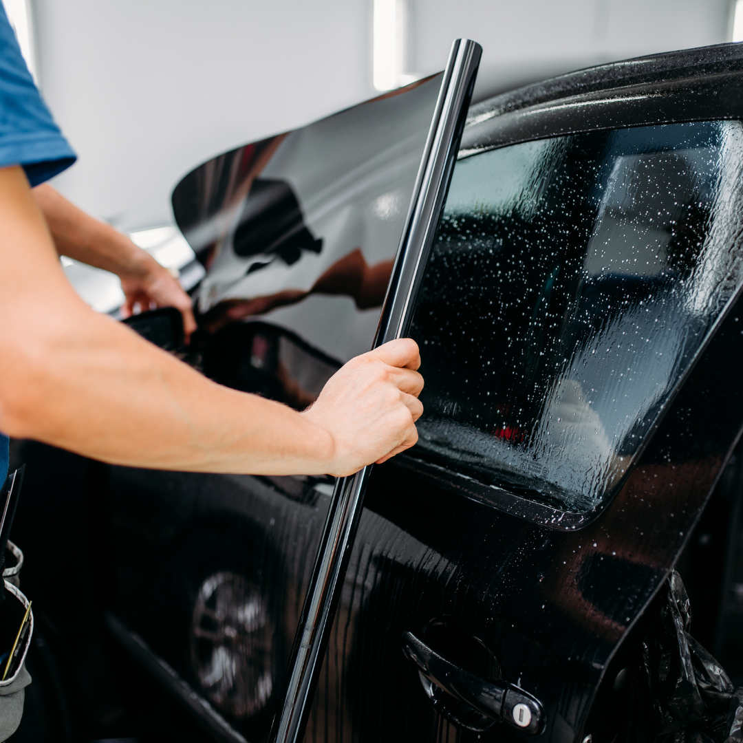 Professional installation of UV-blocking window tint film on a car for heat and glare protection.
