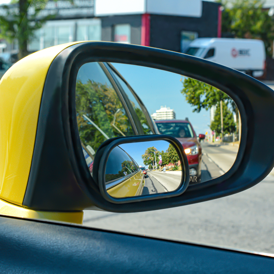 Round blind spot mirror attached to a side mirror, offering enhanced rear and side visibility while driving.